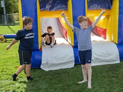 Children cheer at the bottom of an inflatable slide.