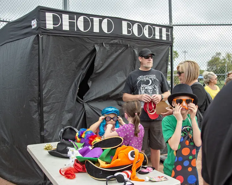 People wait in line trying on costumes before entering a photo booth.