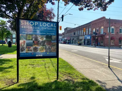 Downtown Brighton with Shop Local sign displaying local businesses displayed in the foreground
