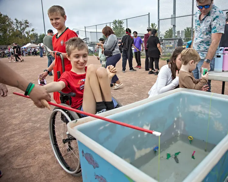 Boy in a wheelchair fishes from the fish pond.