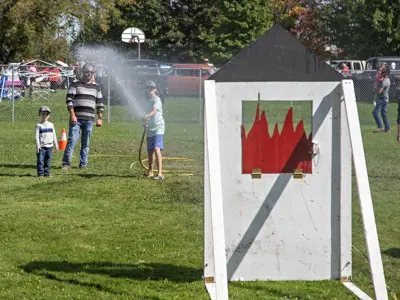 Children fight a fake fire with a real fire hose.